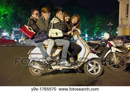 Five young adults cram onto one scooter on the streets of Vietnam at night View Large Photo Image Stock Image - Five young adults cram onto one scooter on the streets of Vietnam at night. Fotosearch