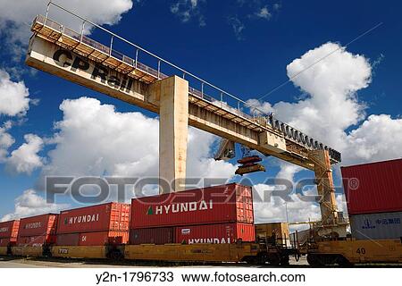 Stock Image - Fixed concrete bridge container crane at a railway transport depot for transfer to trucks. Fotosearch