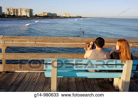 Florida, Cocoa Beach, Cocoa Beach Pier, Atlantic Ocean, bench, man, woman, couple, relax, watching, surfers, waves, feet elevated, railing, View Large Photo Image Stock Image - Florida, Cocoa Beach, Cocoa Beach Pier, Atlantic Ocean, bench, man, woman, couple, relax, watching, surfers, waves, feet elevated, railing,. Fotosearch