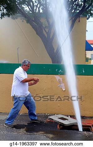 Stock Photo - Florida, Miami Beach, city water main, pipe, break, broken, loss of pressure, leak, spewing, employee, man, Hispanic, cell phone, taking picture, documenting,.. Fotosearch