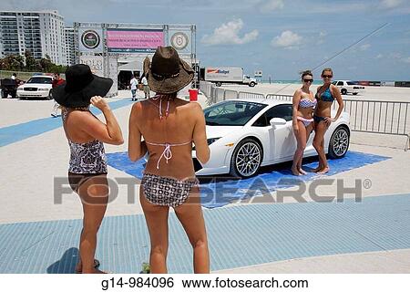 Stock Photograph - Florida, Miami Beach, Polo World Cup Matches, sport, tournament, equestrian event, sand field, sponsor, luxury sports car, Lamborghini, promotion, woman, women, bikini, beachwear, pose,. Fotosearch