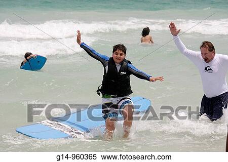 Florida, Miami Beach, South Beach, Atlantic Ocean, Recreation Department Surf Camp, high functioning autism, Aspergers, PDD-NOS, student, counselor, Hispanic, boy, man, teen, surfing, life jacket, vest, learn, coach, teach, fun, smiling, surfboard, View Large Photo Image Stock Photography - Florida, Miami Beach, South Beach, Atlantic Ocean, Recreation Department Surf Camp, high functioning autism, Aspergers, PDD-NOS, student, counselor, Hispanic, boy, man, teen, surfing, life jacket, vest, learn, coach, teach, fun, smiling, surfboard,. Fotosearch