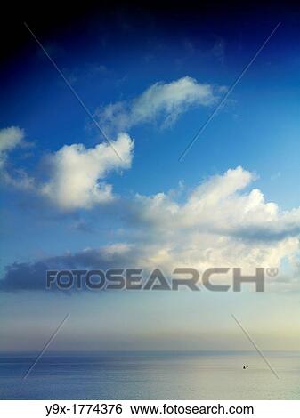 Stock Photograph - Fluffy clouds over the ocean in Bali, Indonesia. Fotosearch
