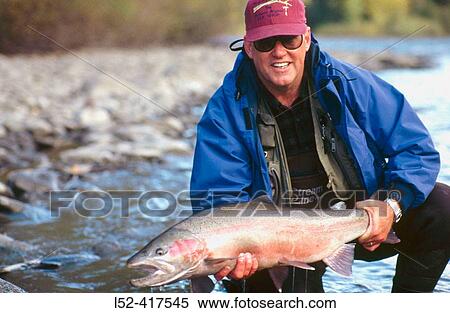 Stock Photography - Fly-fisherman with steelhead, catch and man. Babine river, British Columbia, Canada. Fotosearch