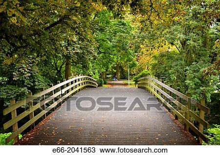 Stock Image - Foot bridge in the Stads Park in Maastricht's old city. Leaves are beginning to change colour in autumn.. Fotosearch