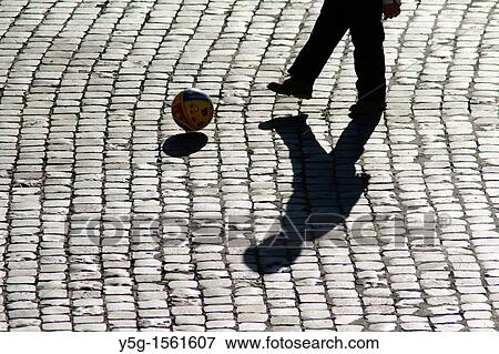 Stock Photo - football player shadow on cobbled street. Fotosearch