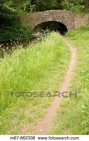 Footpath leading up to old bridge over canal. Wales, UK View Large Photo Image Stock Photo - Footpath leading up to old bridge over canal. Wales, UK. Fotosearch