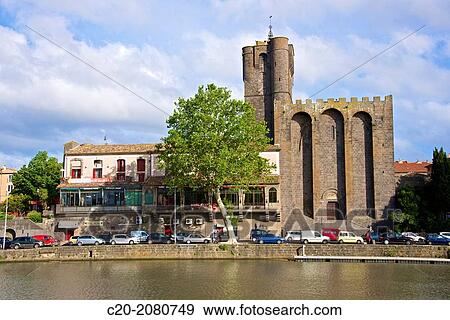 Stock Photo - Fortified Ancienne cath? drale St Etienne, 12thc., built in black lava, and river banks along Herault river, AGDE town, Haut Languedoc, 34 France.. Fotosearch