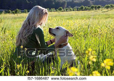 Forty something year old woman sitting in a meadow with her dog View Large Photo Image Stock Photo - Forty something year old woman sitting in a meadow with her dog. Fotosearch