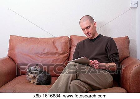 Picture - forty year old man using ipad tablet in casual setting. Fotosearch