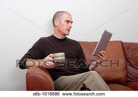 Stock Photograph - forty year old man using ipad tablet in casual setting. Fotosearch