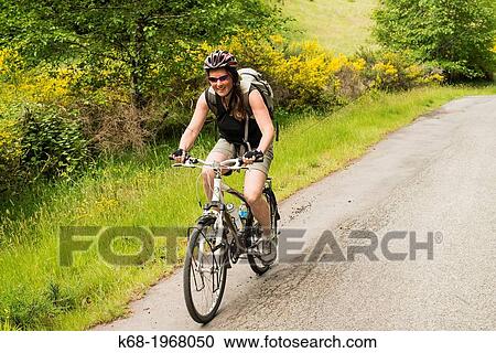 Stock Image - forty year old woman bicycles on Saturna Island, Gulf Islands, BC, Canada. Fotosearch