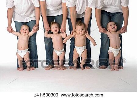 Stock Photo - Four babies standing with their parents help. Fotosearch