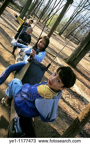 Four children playing on a log swing in a public park, Peaugres, France. View Large Photo Image Stock Image - Four children playing on a log swing in a public park, Peaugres, France.. Fotosearch
