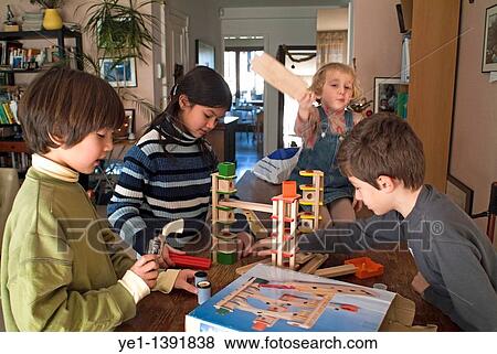 Four children playing together a game on a table in their living room, France View Large Photo Image Stock Photo - Four children playing together a game on a table in their living room, France. Fotosearch