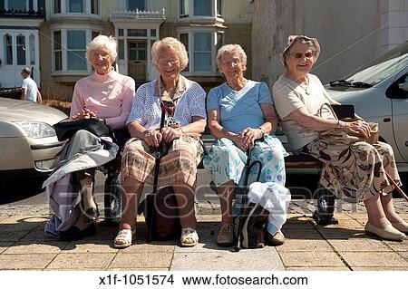Four elderly women ojn a day trip to the seaside, sitting on a bench on summer afternoon View Large Photo Image Picture - Four elderly women ojn a day trip to the seaside, sitting on a bench on summer afternoon. Fotosearch