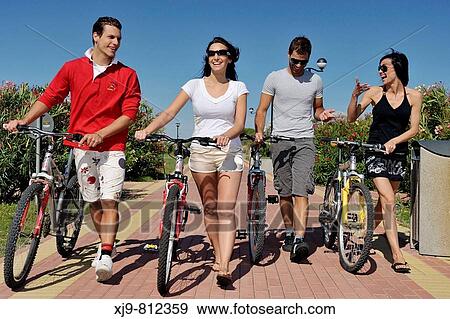 Four friends walking and pushing bikes. View Large Photo Image Stock Photo - Four friends walking and pushing bikes.. Fotosearch