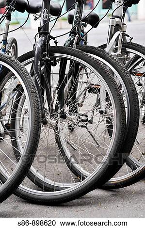 Stock Image - Four parked bicycles, close-up of front tires. Fotosearch