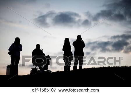 Four people, one in a wheelchair, silhouetted against the sky, Aberystwyth at dusk, October 2011 View Large Photo Image Stock Photo - Four people, one in a wheelchair, silhouetted against the sky, Aberystwyth at dusk, October 2011. Fotosearch