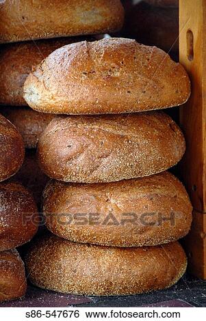 Stock Photograph - Four, round, vertically stacked loaves of bread, in a display case, at a farmet's market. Fotosearch