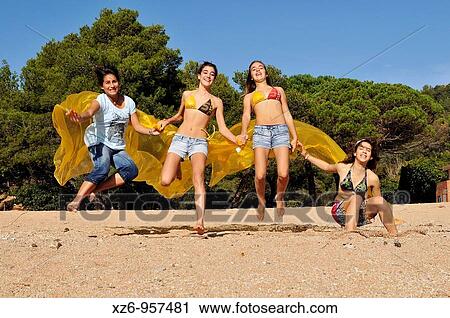 Four teenage girls jumping on the beach with yellow cloths View Large Photo Image Stock Image - Four teenage girls jumping on the beach with yellow cloths. Fotosearch