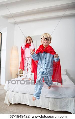 Four year old boy jumping off the bed in a red cape View Large Photo Image Stock Image - Four year old boy jumping off the bed in a red cape. Fotosearch