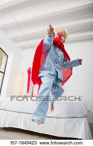 Four year old boy jumping off the bed in a red cape View Large Photo Image Stock Image - Four year old boy jumping off the bed in a red cape. Fotosearch