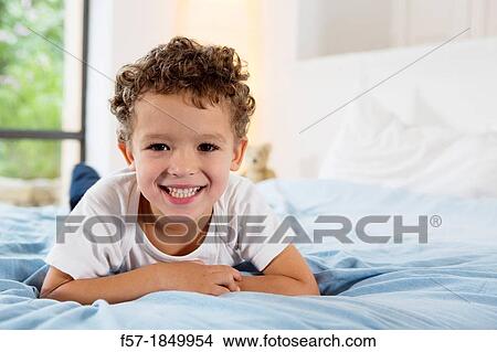 Four year old boy lying on a bed View Large Photo Image Picture - Four year old boy lying on a bed. Fotosearch
