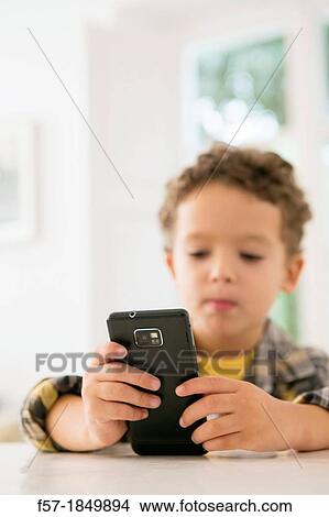 Four year old boy playing games on a cell phone View Large Photo Image Picture - Four year old boy playing games on a cell phone. Fotosearch