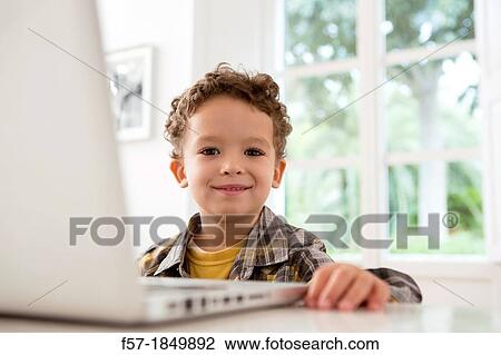 Stock Image - Four year old boy playing games on a laptop. Fotosearch