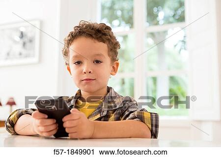 Stock Image - Four year old boy playing games on a cell phone. Fotosearch