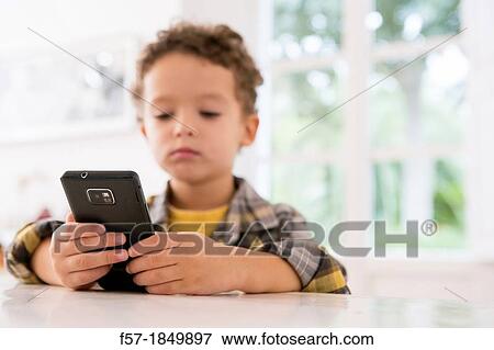 Stock Photo - Four year old boy playing games on a cell phone. Fotosearch