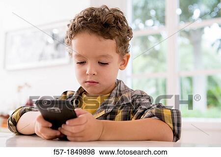 Four year old boy playing games on a cell phone View Large Photo Image Stock Photo - Four year old boy playing games on a cell phone. Fotosearch