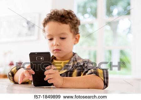Four year old boy playing games on a cell phone View Large Photo Image Stock Photo - Four year old boy playing games on a cell phone. Fotosearch