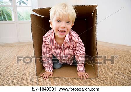 Stock Image - Four year old boy playing in a cardboard box. Fotosearch