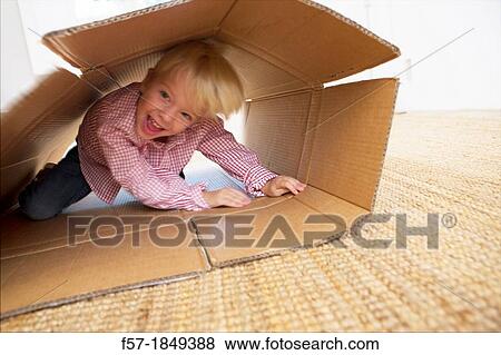 Stock Photo - Four year old boy playing in a cardboard box. Fotosearch