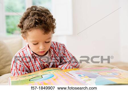 Four year old boy reading a book on the sofa View Large Photo Image Stock Photo - Four year old boy reading a book on the sofa. Fotosearch