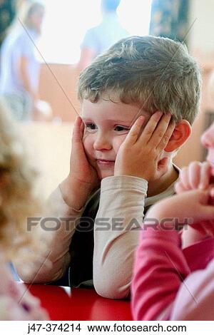 Four year old boy sitting at table with other children at nursrey school View Large Photo Image Picture - Four year old boy sitting at table with other children at nursrey school. Fotosearch
