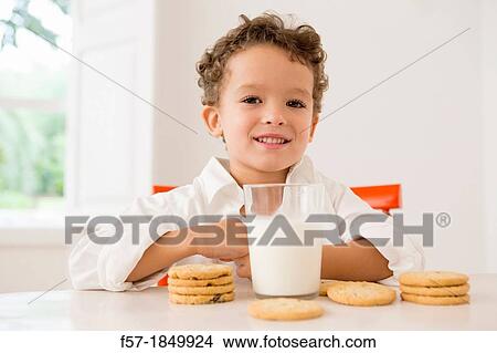 Picture - Four year old boy with milk and cookies for breakfast. Fotosearch