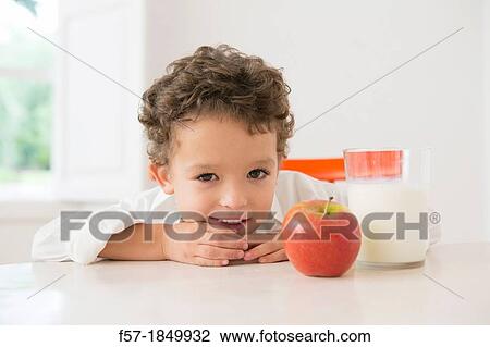 Stock Image - Four year old boy with milk and fruit for beakfast. Fotosearch