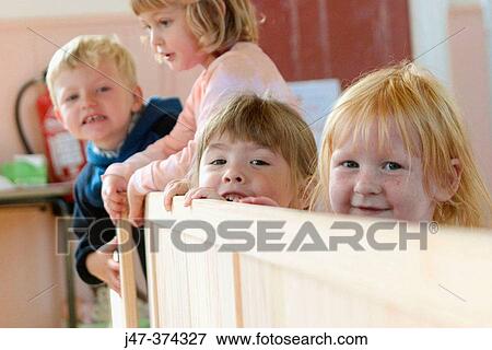 Four year old children peeping over fence at nursrey school View Large Photo Image Stock Photo - Four year old children peeping over fence at nursrey school. Fotosearch