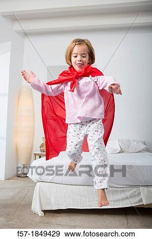 Four year old girl jumping off the bed in a red cape View Large Photo Image Stock Photo - Four year old girl jumping off the bed in a red cape. Fotosearch