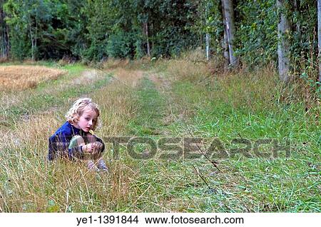 Four year old girl sitting alone in the grass beside a forest, France View Large Photo Image Picture - Four year old girl sitting alone in the grass beside a forest, France. Fotosearch