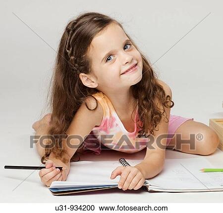 Stock Image - Four year old girl smiling at the camera ready to do homework. Fotosearch