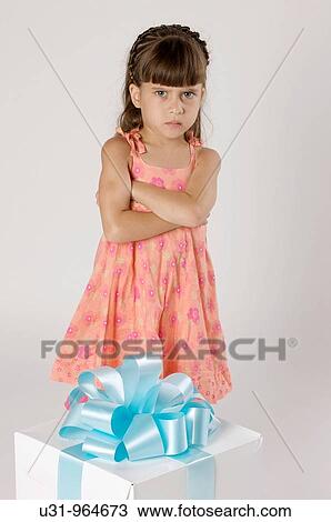 Stock Image - Four year old girl with a big present in a studio setting looking angry. Fotosearch