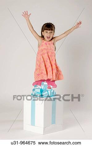 Stock Photography - Four year old girl with a big present in a studio setting. Fotosearch