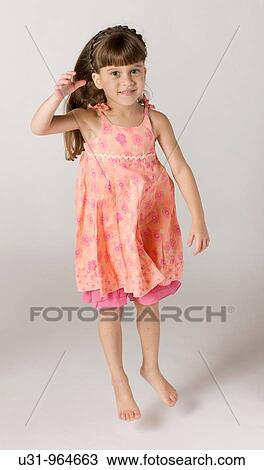 Stock Image - Four year old jumping happily in a studio setting. Fotosearch