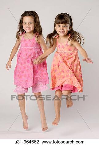 Stock Image - Four year old twins jumping happily in a studio setting. Fotosearch