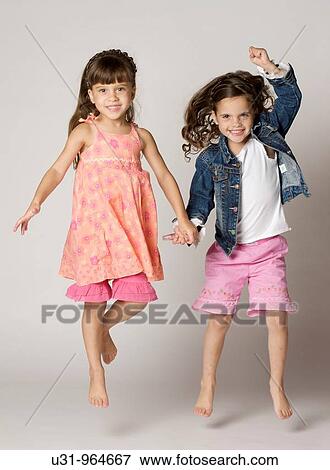 Stock Photo - Four year old twins jumping happily in a studio setting. Fotosearch