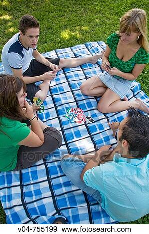 Four young people playing cards in the garden View Large Photo Image Stock Photo - Four young people playing cards in the garden. Fotosearch